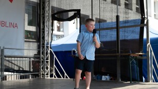 Chłopiec w niebieskiej koszuli deklamuje wiersz przy mikrofonie
