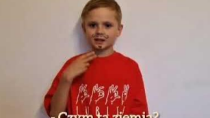 chłopiec w czerwonej koszulce z napisem w języku migowym fonogestuje słowa 