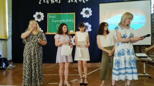 nauczycielki wręczają nagrody uczennicom podczas zakończenia roku szkolnego. jedna z nauczycielek tłumaczy na język migowy